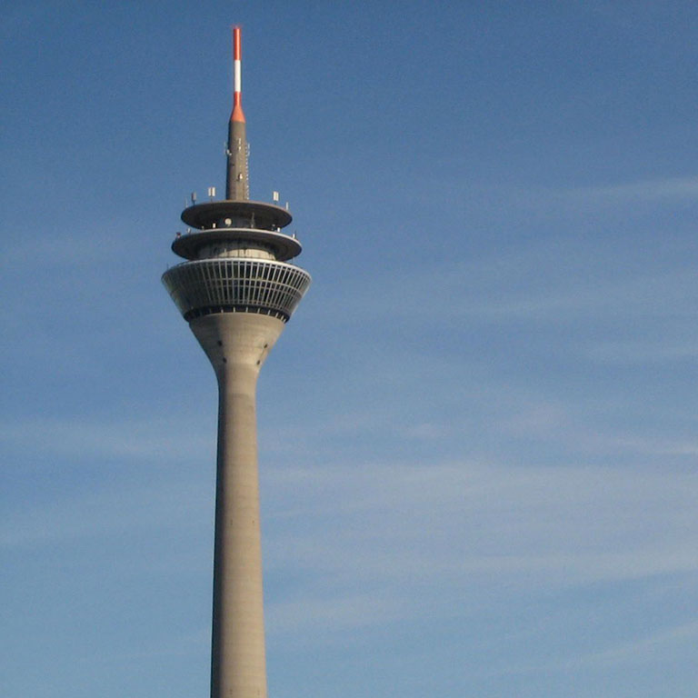 The top of the Düsseldorf TV Tower against a blue sky.