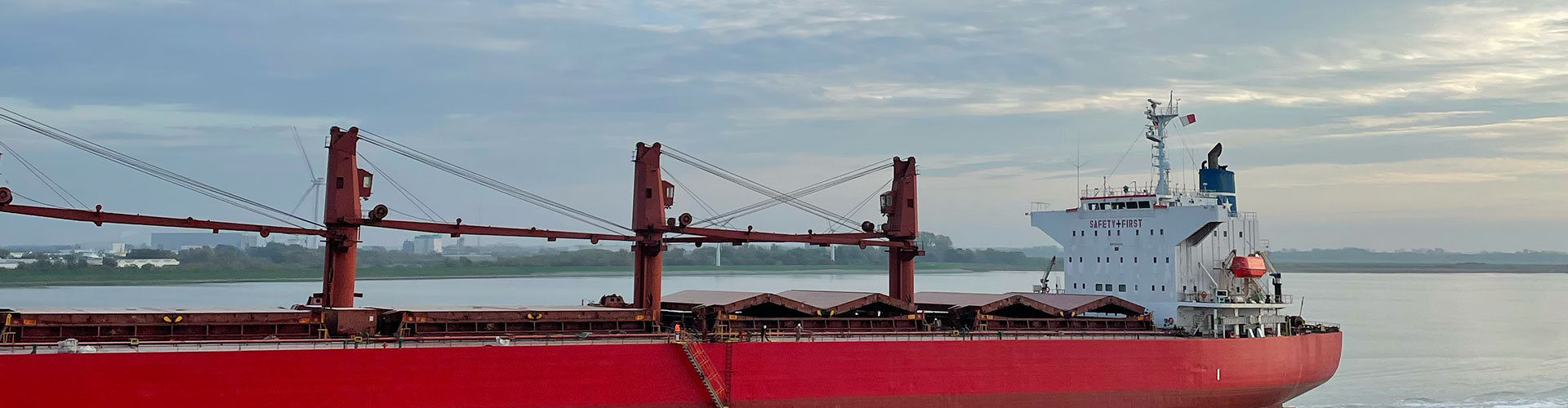 A red cargo ship in front of an evening sky.